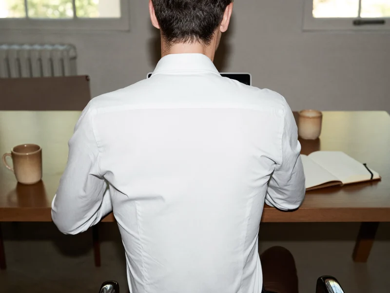 Professionista alla scrivania con portatile, taccuino e tazza in ceramica